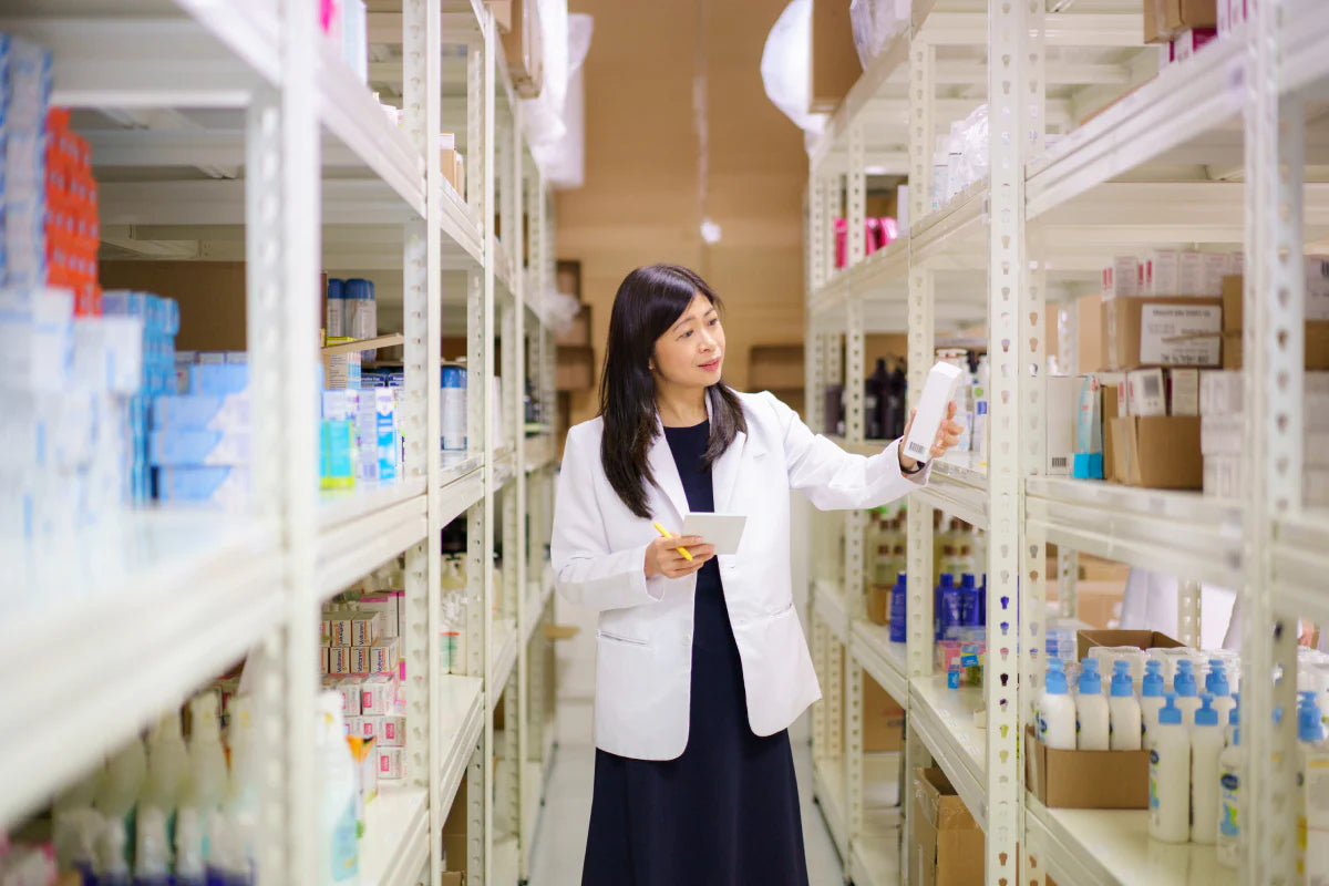 Glovida pharmacist checking out medicines in between 2 racks